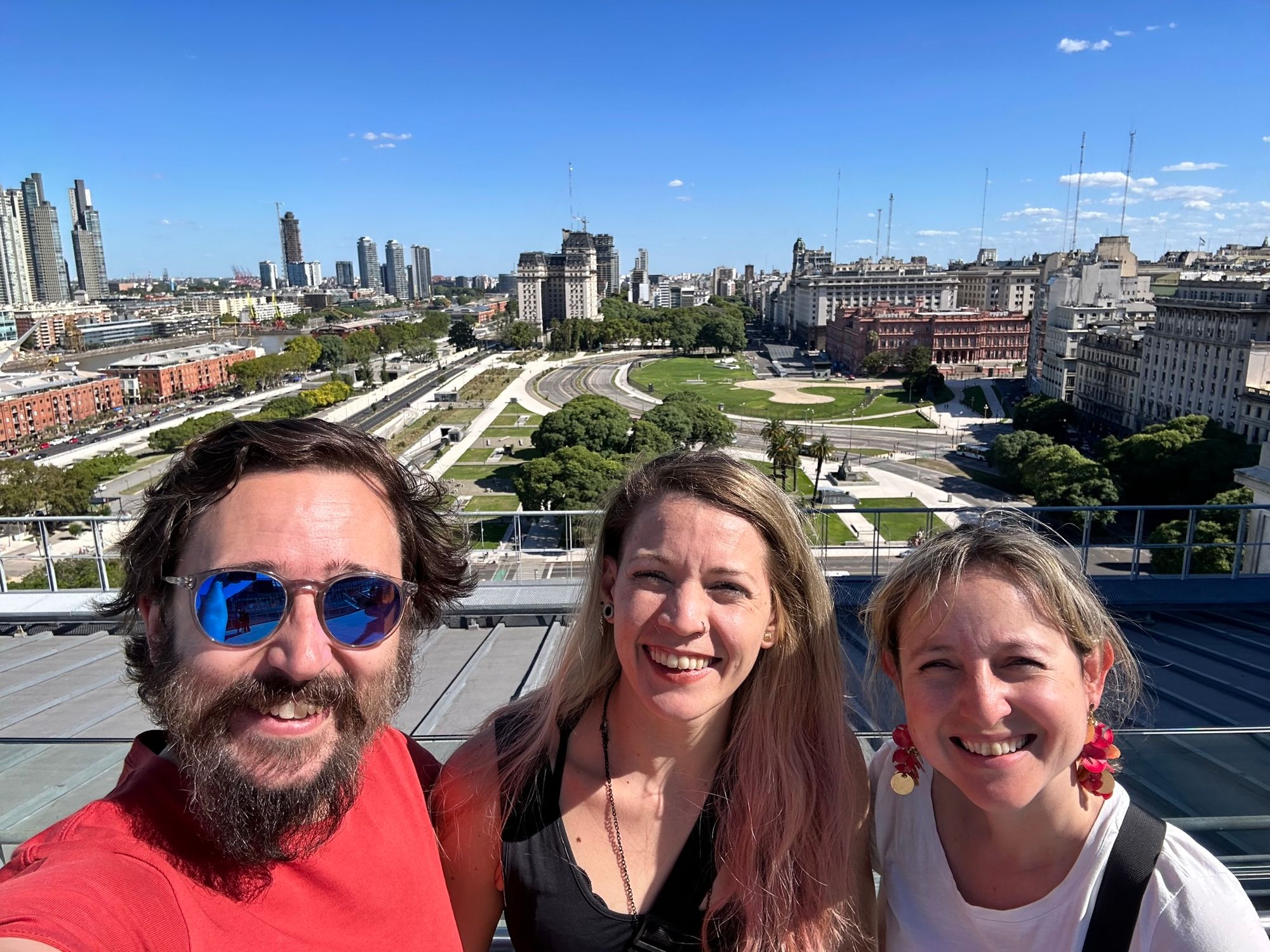 JP, Cheryl, and Yvette grinning in the sun on the top of the Kirchner cultural centre.